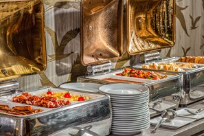 A buffet with various food options and stacked plates. - Charm Hotel Budapest  (formerly Boutique Hotel Budapest) (Budapest)