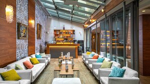 Un espacio lounge moderno con sofás, un bar y techo de cristal.