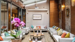 Un moderno vestíbulo de hotel con mostrador de recepción, zona de estar con sofás y sillones, área de bar y un letrero que indica el nombre del hotel.
