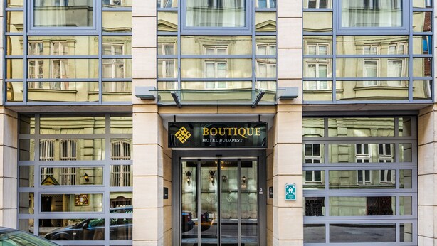 La entrada del Hotel Boutique Budapest, con fachada de vidrio y varias ventanas.