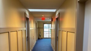 A hotel corridor with a blue carpet, beige walls, and doors on both sides. - Canadian Inn (Surrey)