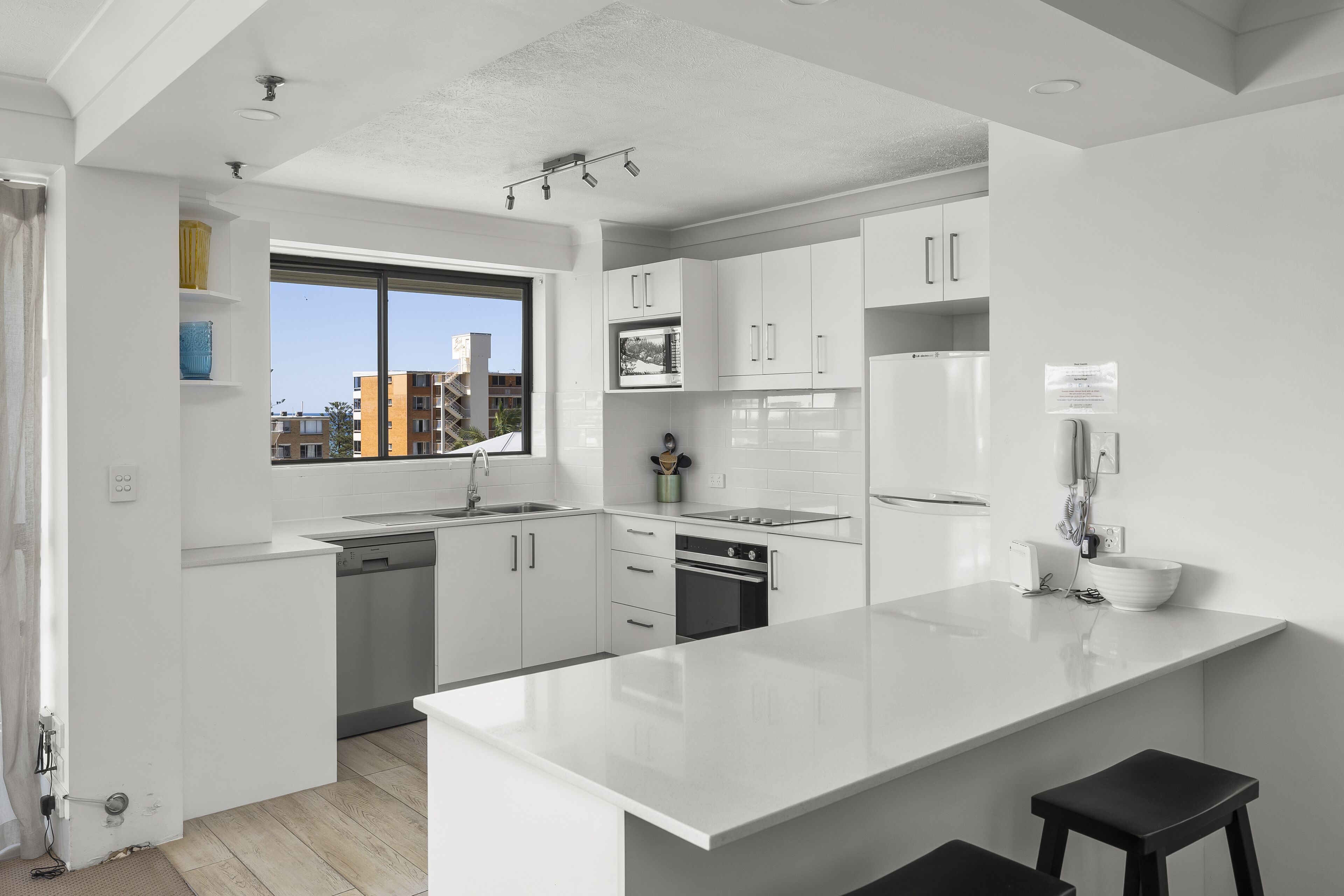 Una cucina moderna con mobili bianchi, una grande isola e una finestra con vista sulla città.