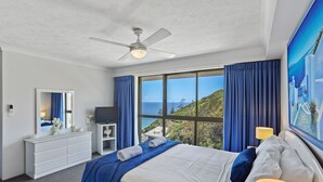 Een hotelkamer met een bed, een dressoir, een televisie en een groot raam met gordijnen.
