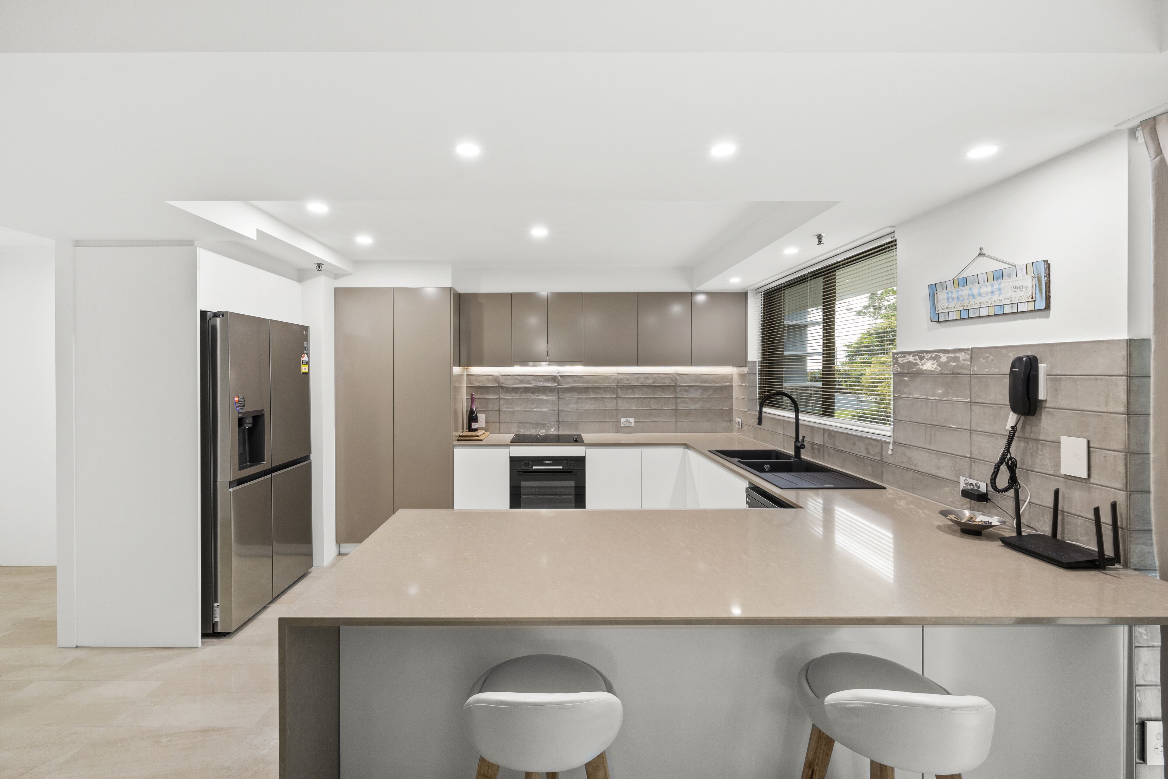 A modern kitchen with a central island, stainless steel appliances, and a hanging telephone.