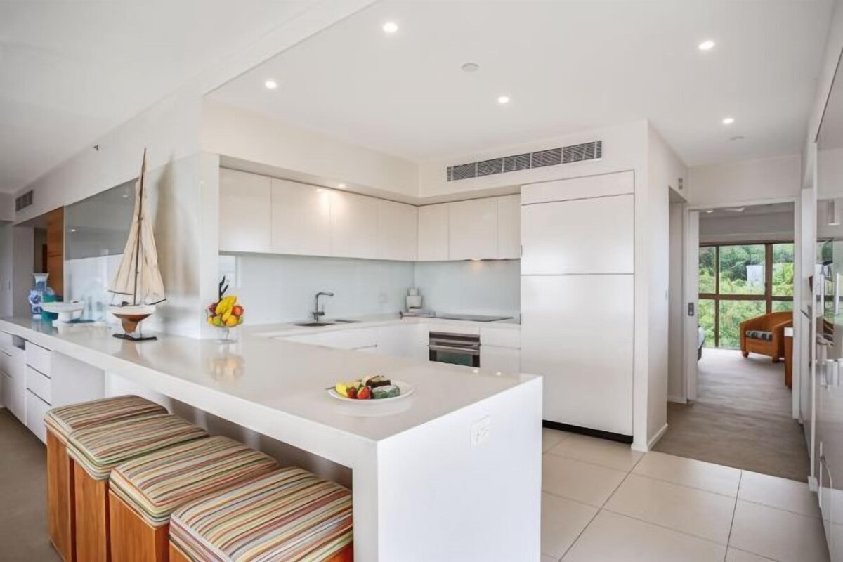 A modern kitchen with a central island, white cabinetry, and a view to the outdoors.