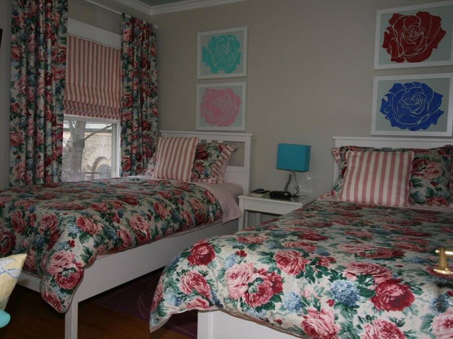 Un dormitorio con dos camas, ropa de cama estampada, una ventana con cortinas y decoración en la pared.