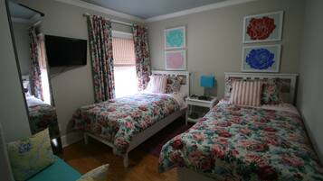 A bedroom with two beds, a TV, and a nightstand with a lamp.