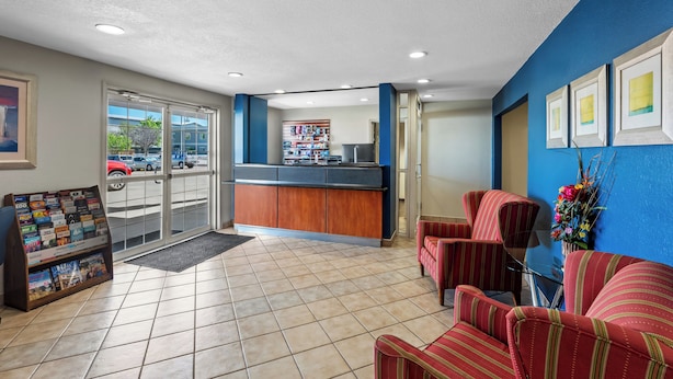 A reception area with a counter, seating, a magazine rack, and a view of the parking lot. - Rodeway Inn (Temple)