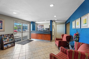 A reception area with a counter, seating, and a view of the parking lot. - Rodeway Inn (Temple)