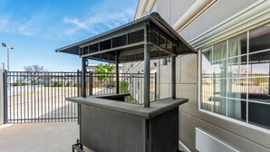 A covered outdoor area with a metal structure, a gated entrance, and a building with large windows. - Rodeway Inn (Temple)