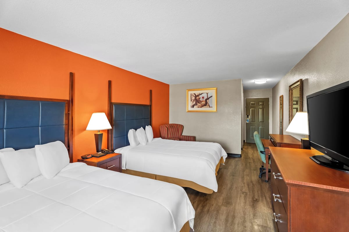 A hotel room with two beds, a TV, a desk, and a chair.