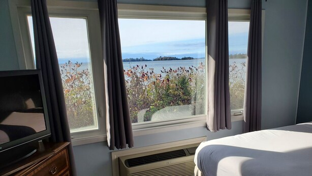 Un dormitorio con cama, televisor, ventana con cortinas y aire acondicionado.