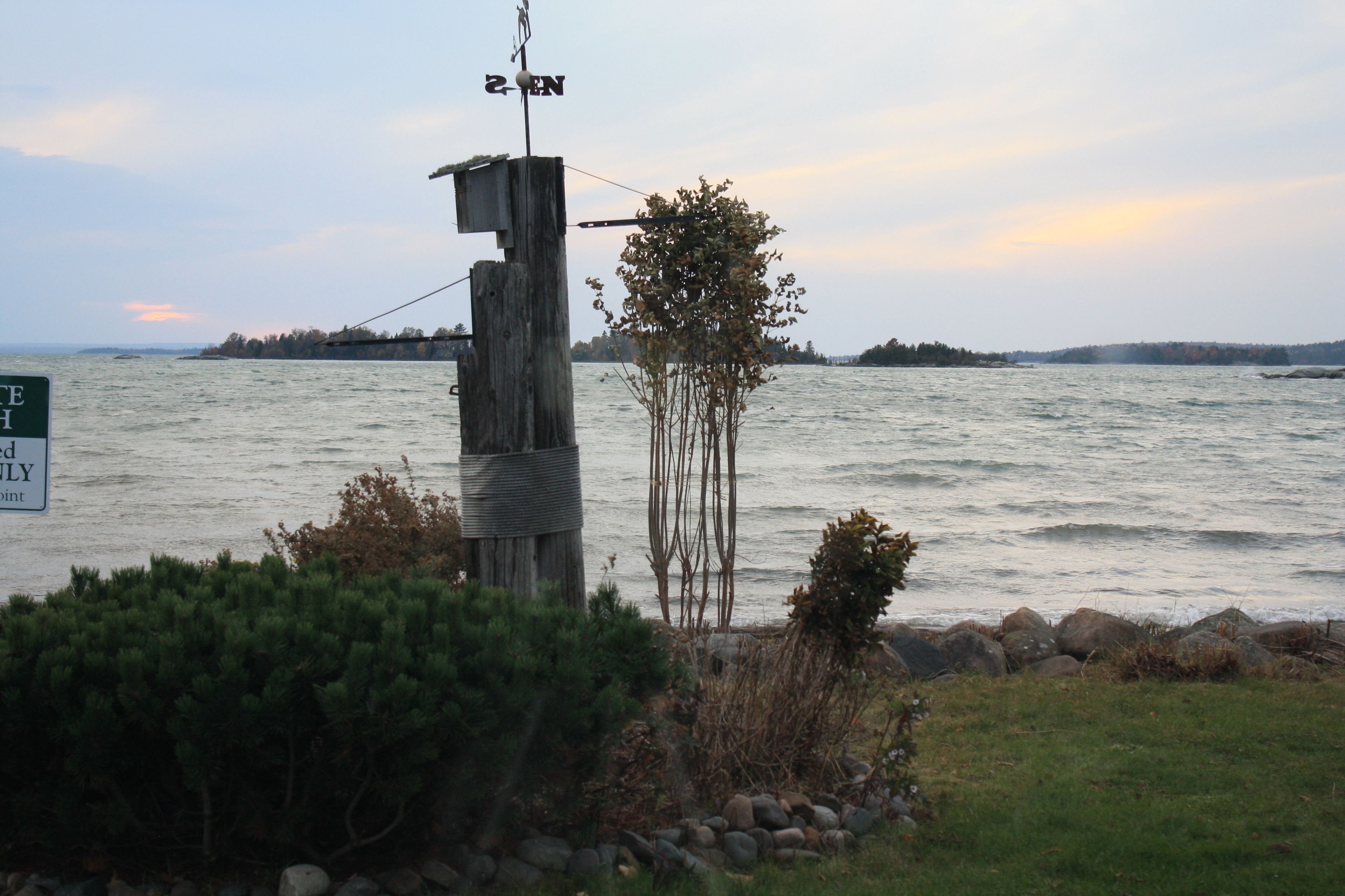 A wooden post with a weather vane and a sign indicating a point of interest.