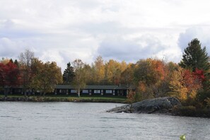 A lakeside lodge with a green roof, surrounded by autumn foliage. - Carolyn Beach Inn & Restaurant (Thessalon)