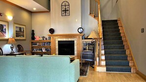 A living room with a fireplace, bookshelves, a staircase, and a dining area. - Country Inn & Suites by Radisson, El Dorado, AR (El Dorado)