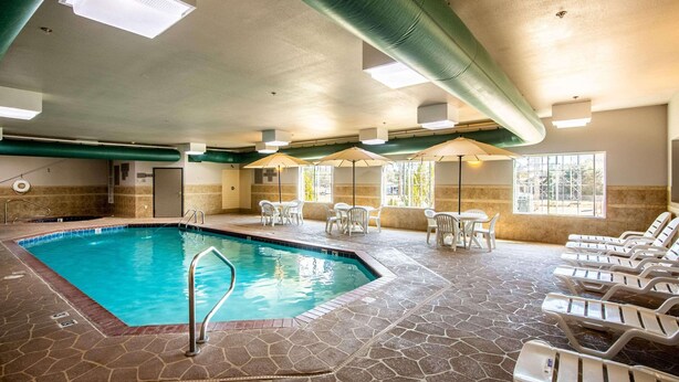 An indoor swimming pool with a stone floor, lounge chairs, and a ceiling with exposed ductwork. - Country Inn & Suites by Radisson, El Dorado, AR (El Dorado)