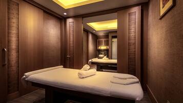 A modern spa room with a massage table, wooden paneling, and a mirror reflecting the room.