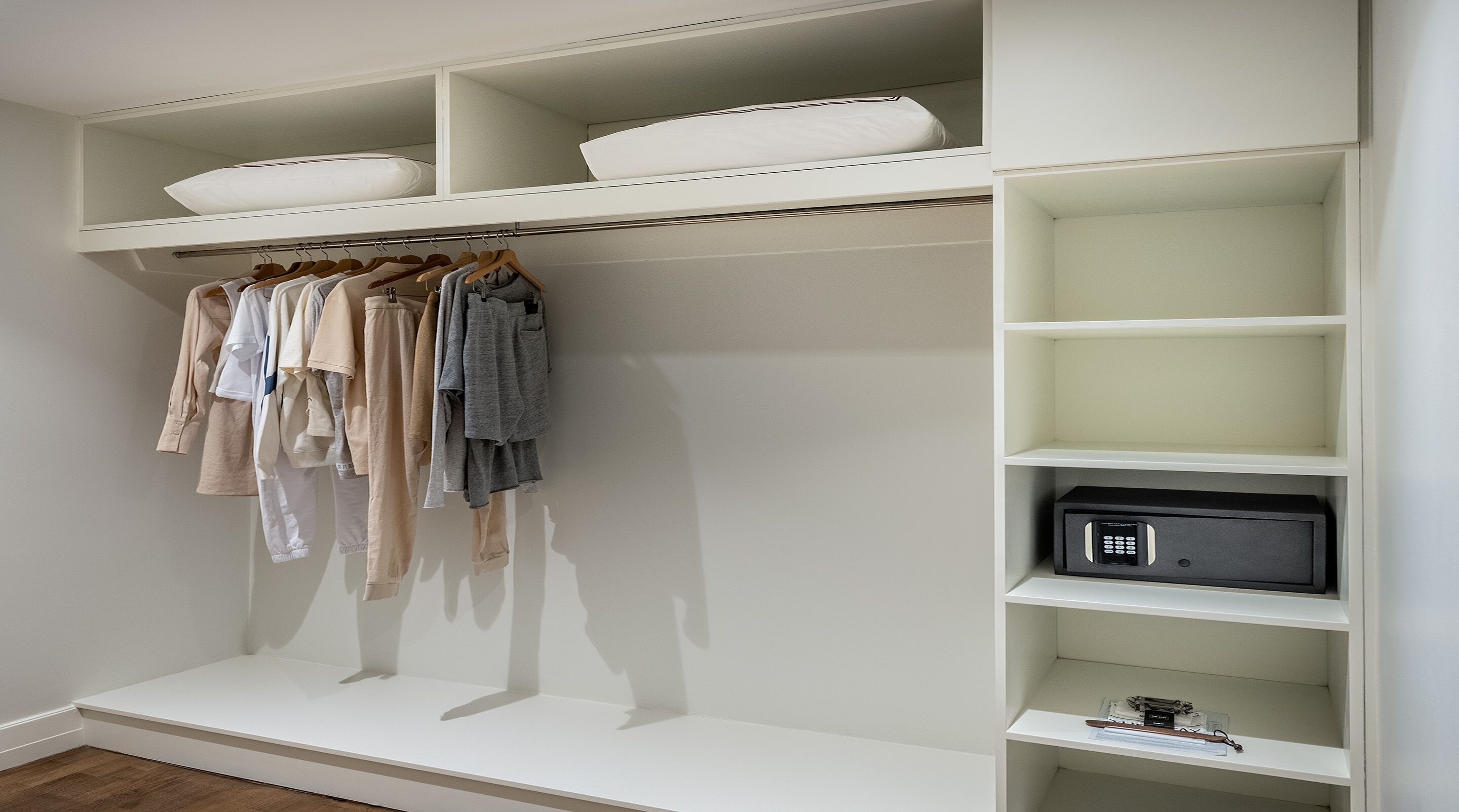 A walk-in closet with hanging clothes, shelves, and a microwave.