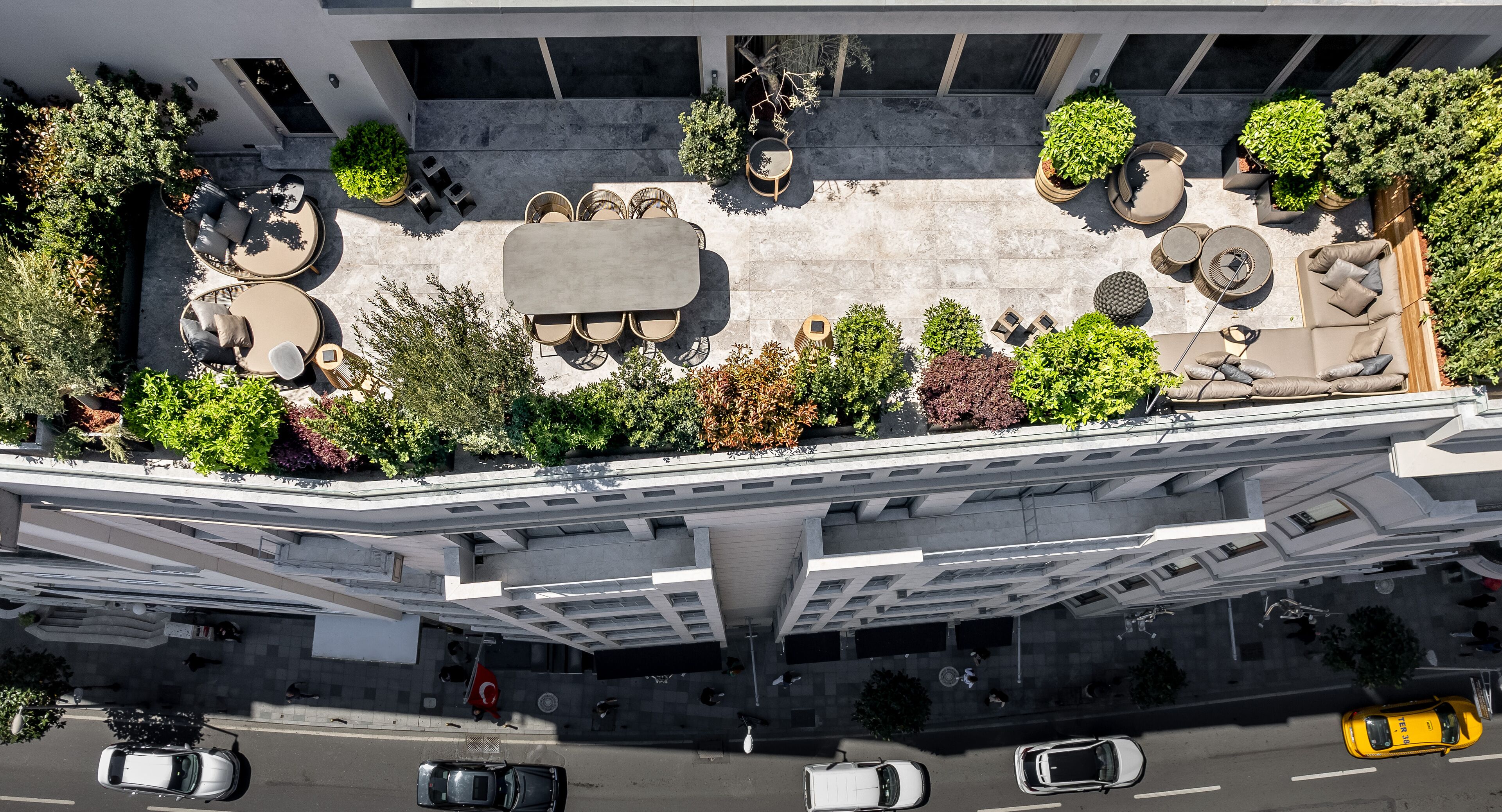 Vue aérienne d’un jardin aménagé sur un toit, avec un espace extérieur pour s’asseoir, le tout entouré d’une structure architecturale moderne.