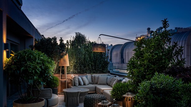 An outdoor seating area with a sofa, round tables, and potted plants. - The Stay Boulevard Nisantasi (Istanbul)