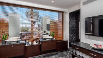 A modern bathroom with two sinks, wooden blinds, a large mirror, and a TV.