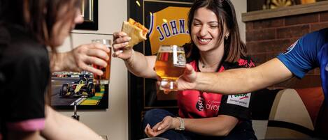 A person holding a glass of beer and a slice of pizza.