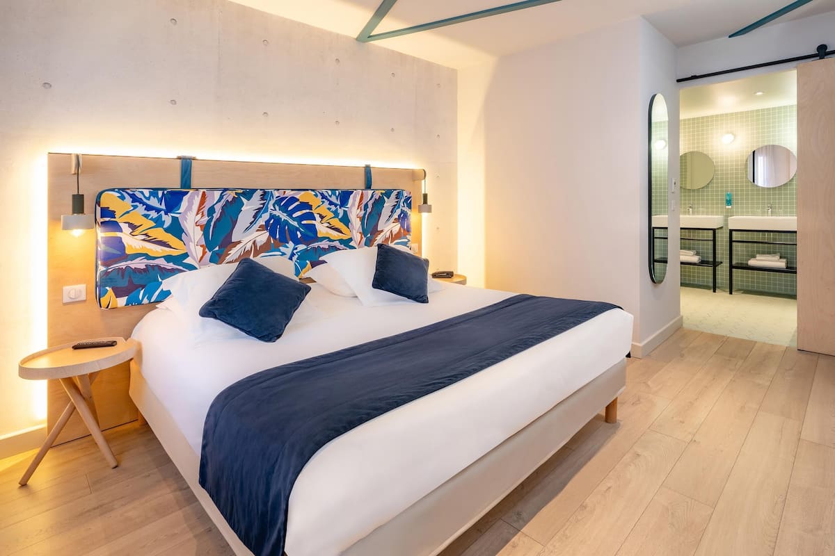 Une chambre d’hôtel moderne avec un grand lit, une table de chevet et une vue sur la salle de bain.