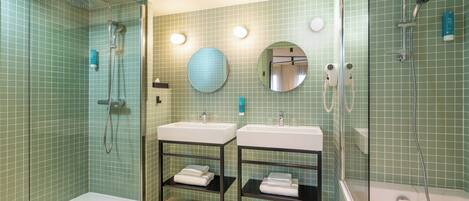 Un baño con dos lavamanos, ducha y zona de ducha con mampara de cristal.
