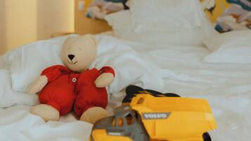 Un lit avec un ours en peluche et un jouet représentant un véhicule.