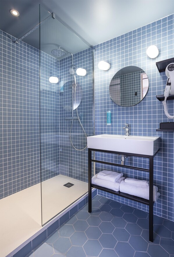 A modern bathroom with a glass-enclosed shower, a white sink, and a mirror.