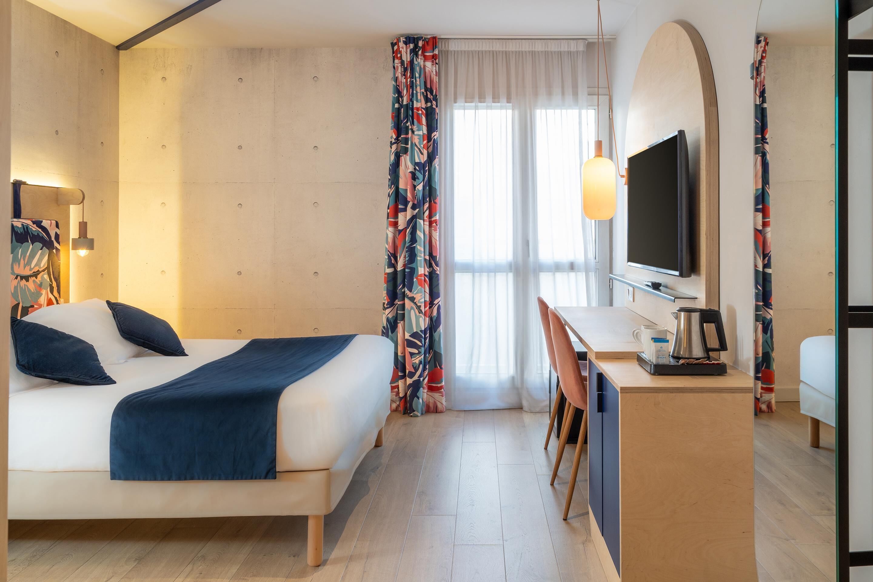 A hotel room with a bed, desk, and TV.
