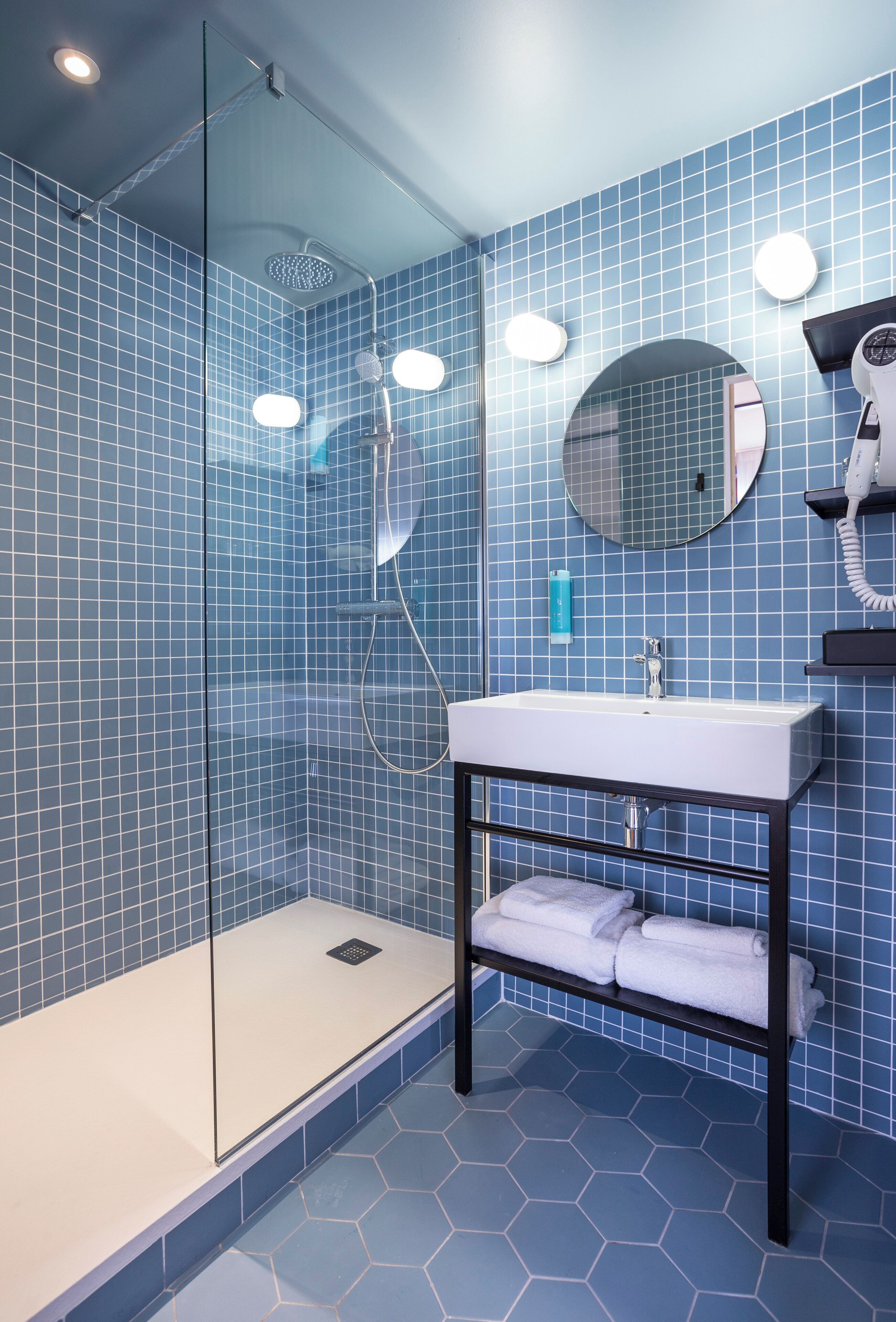 A modern bathroom with a glass-enclosed shower, a white sink, and a mirror.