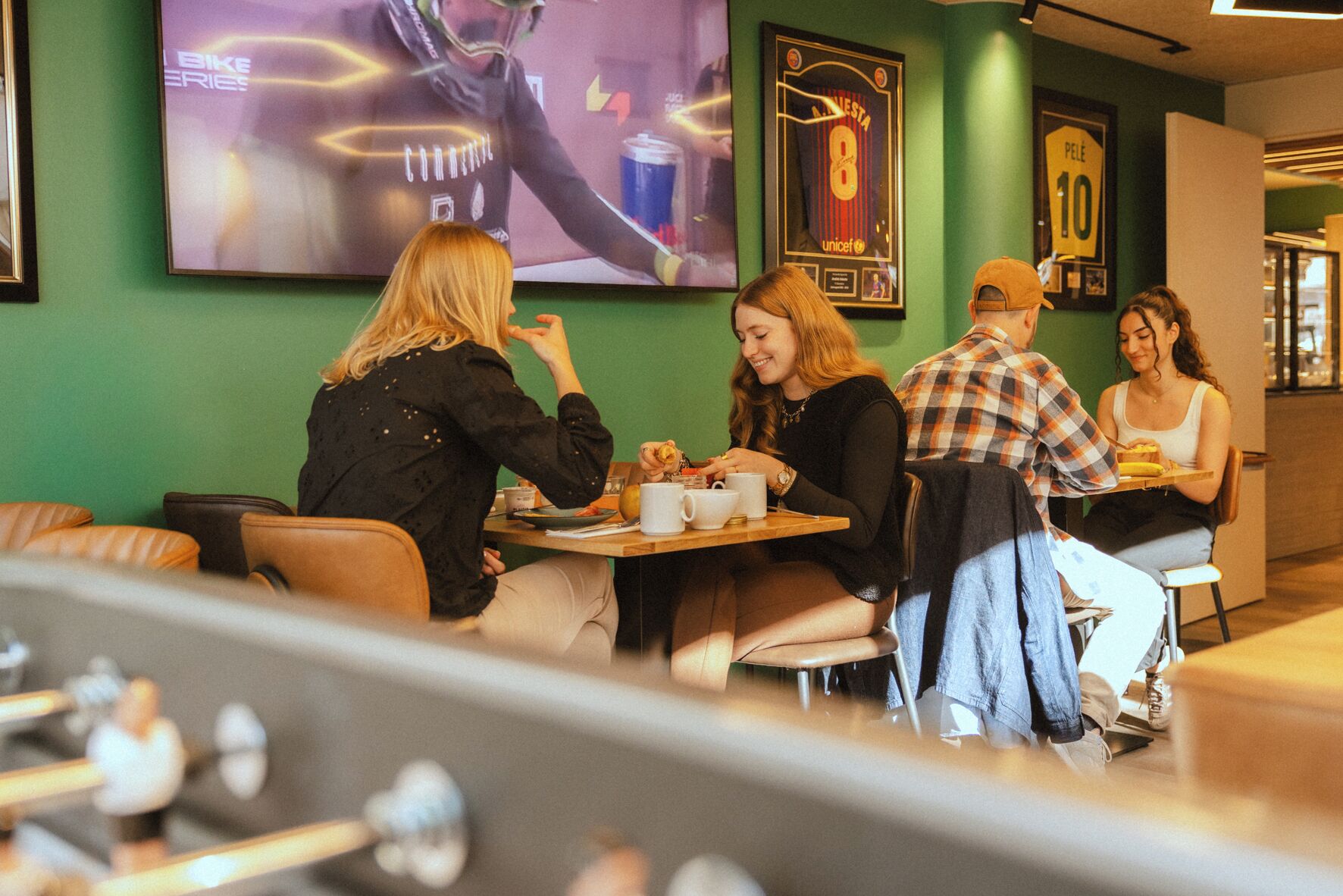 Eine Gruppe von Menschen speist in einem Restaurant mit grünen Wänden und gerahmten Sportmemorabilien.