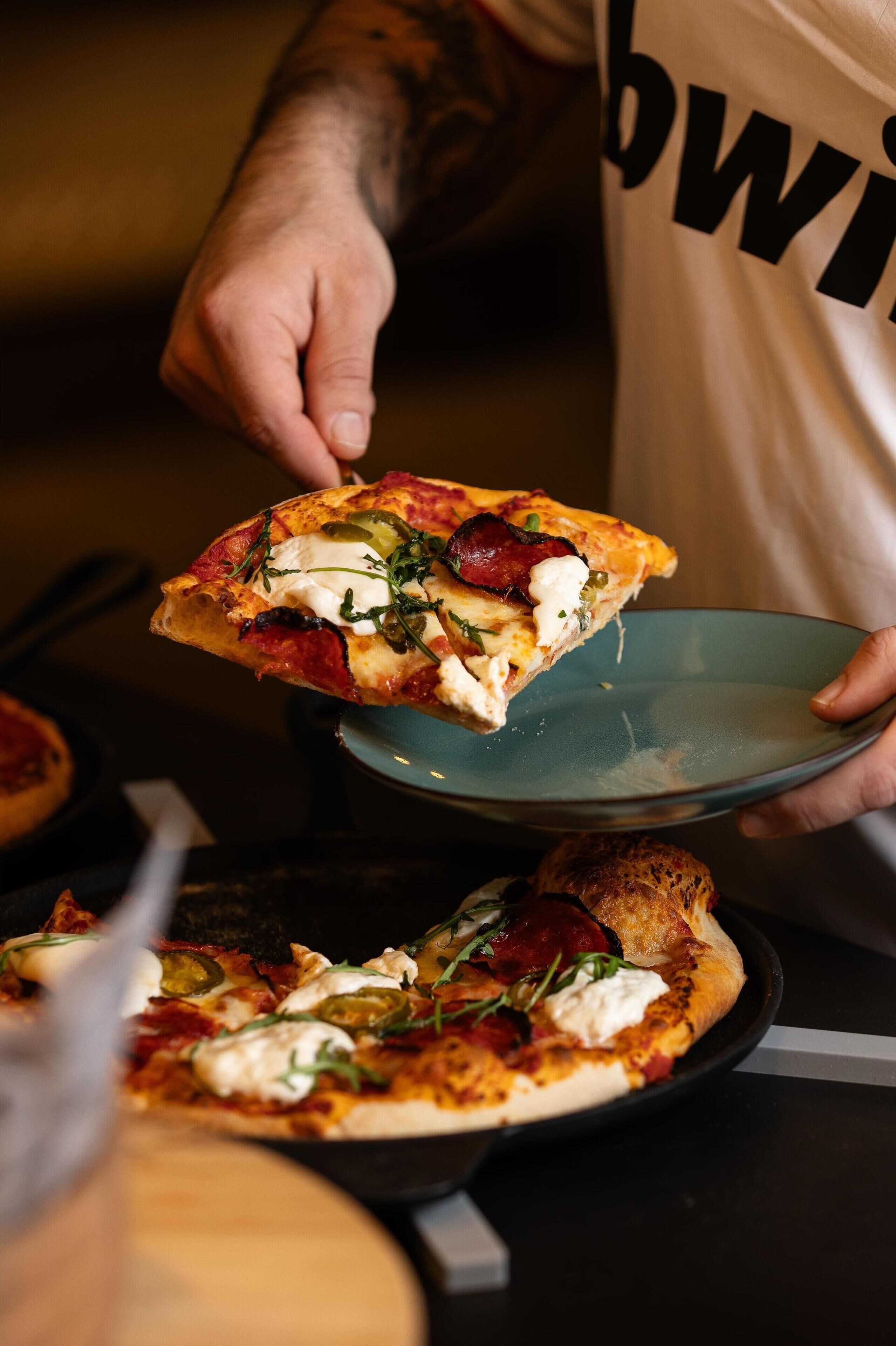 A person holding a slice of pizza with toppings.
