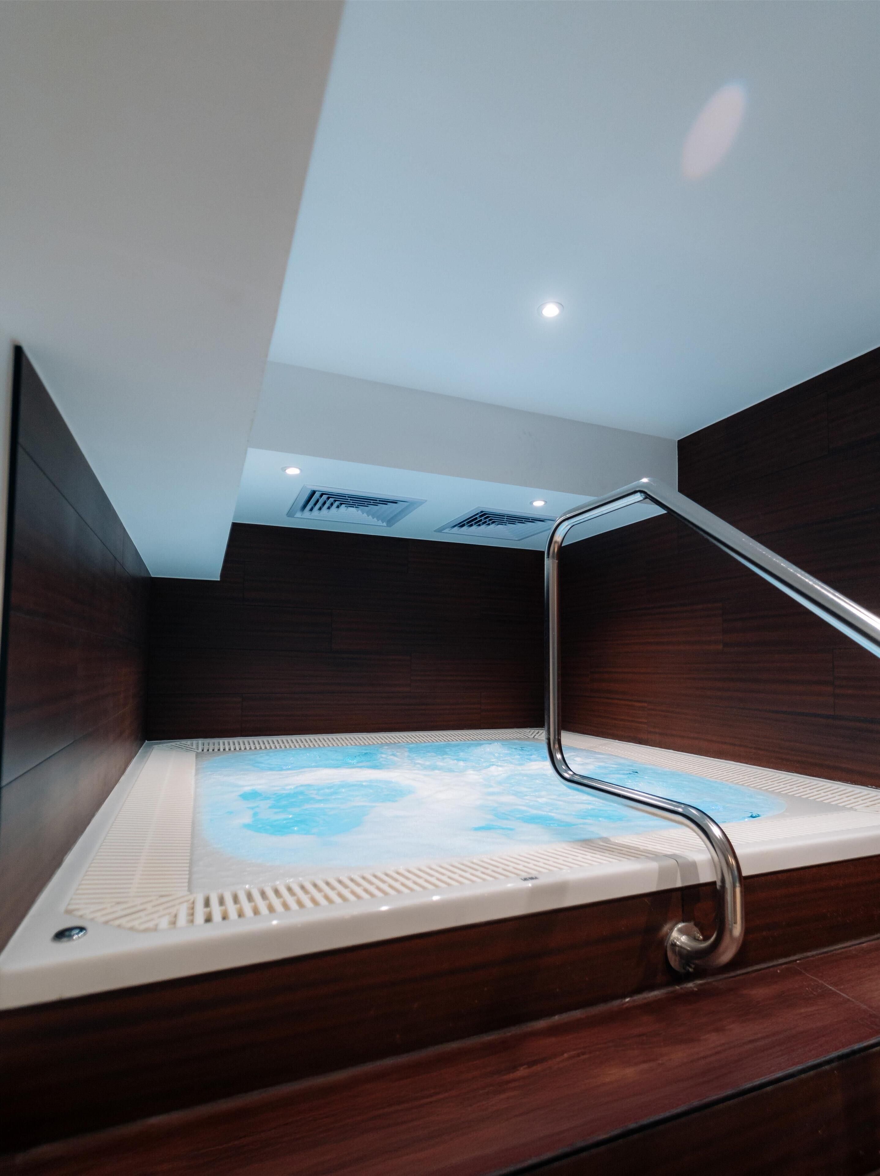 Une salle de bain moderne avec un meuble-lavabo en bois, une baignoire intégrée et un plafond doté d’un éclairage encastré.