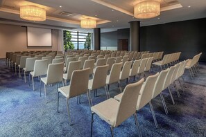 A conference room with rows of chairs, a projector screen, and large windows. - Hotel Evian-les-Bains by Leonardo Hotels (Evian-les-Bains)