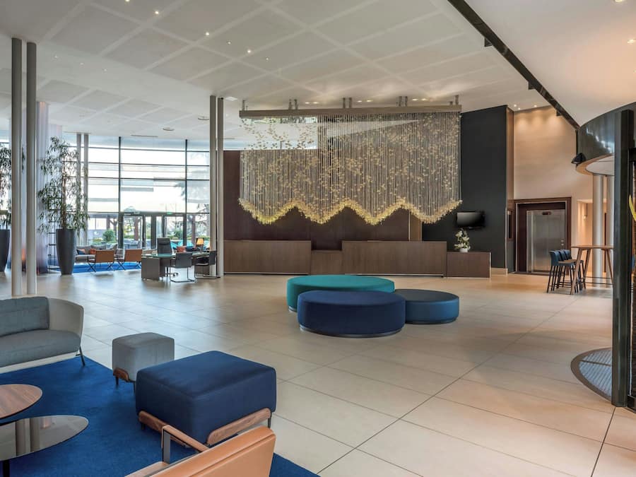 Un lobby amplio con mobiliario moderno, una lámpara de araña grande y una mesa de recepción.