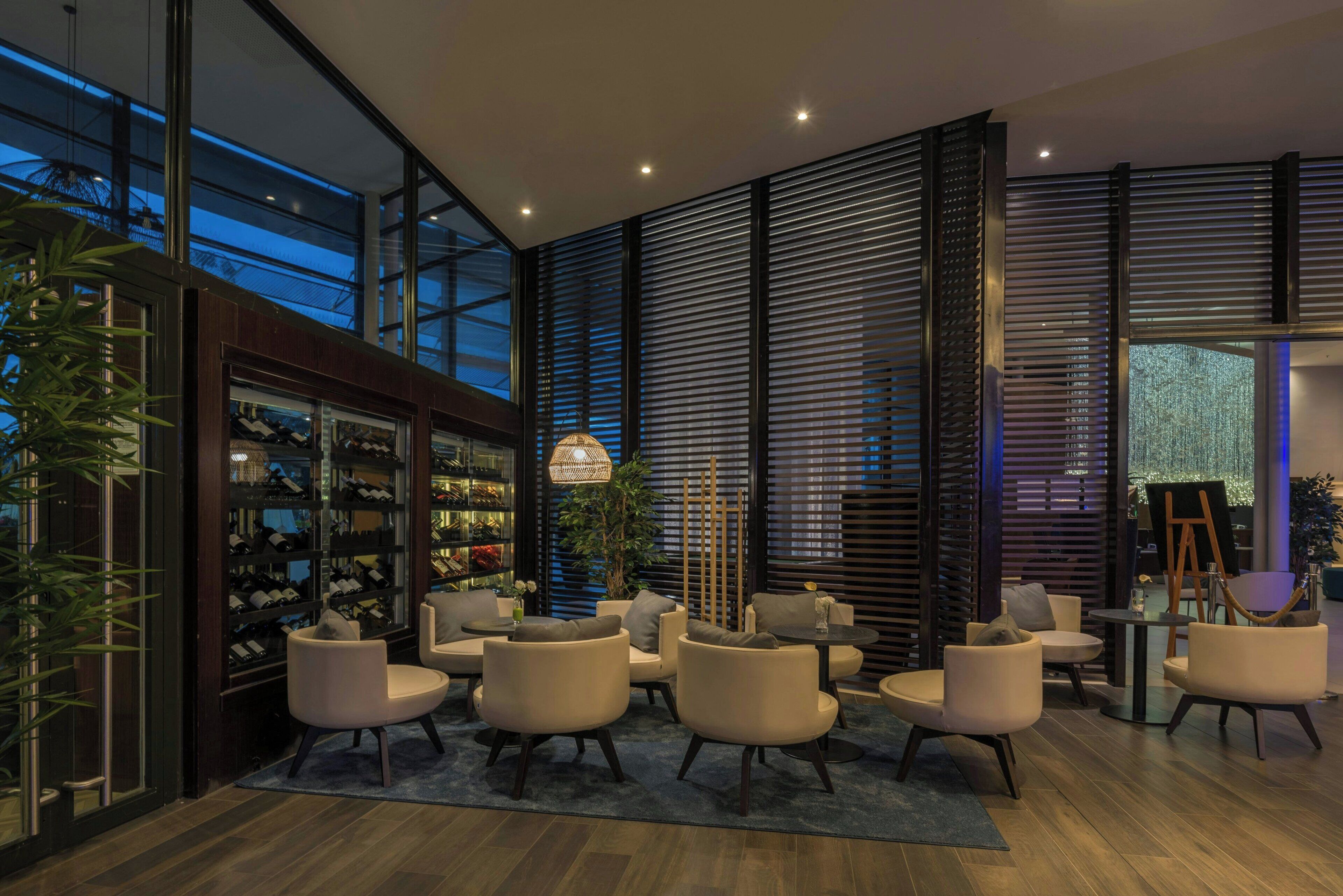 A modern interior with a wine rack, seating area, and large windows.