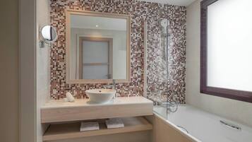 Un baño moderno con un espejo grande, un lavamanos sobre encimera, cabina de ducha y ventana.
