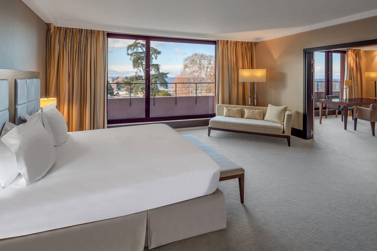Une chambre d’hôtel avec un grand lit, un canapé, une table à manger et une vue sur l’extérieur.
