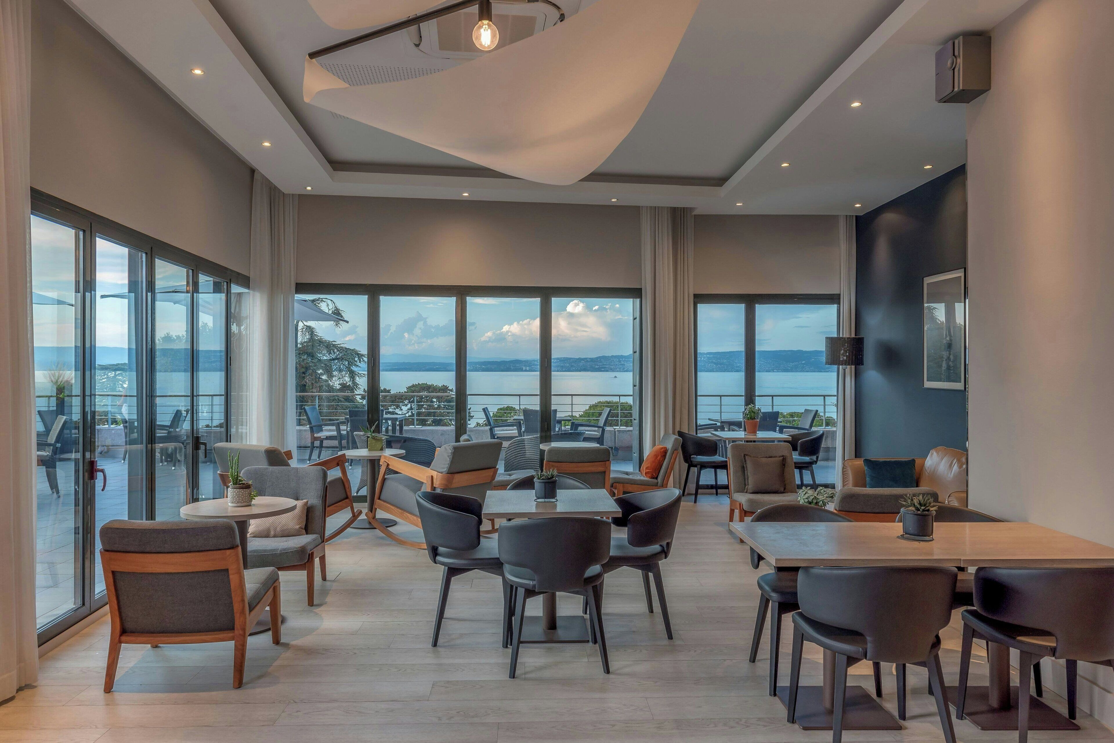 Un espacio interior amplio con diversas opciones de mobiliario, ventanas grandes que ofrecen vistas al exterior y un diseño de techo moderno.