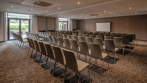 A conference room with rows of chairs, a projector screen, and a large window. - Hotel Evian-les-Bains by Leonardo Hotels (Evian-les-Bains)