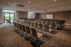 A conference room with rows of chairs, a projector screen, and a large window. - Hotel Evian-les-Bains by Leonardo Hotels (Evian-les-Bains)