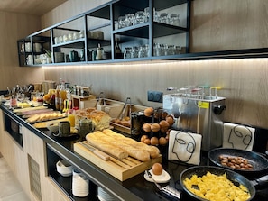 A buffet setup with various food items, utensils, and a large stainless steel pot. - Villa Berlioz (Lyon)
