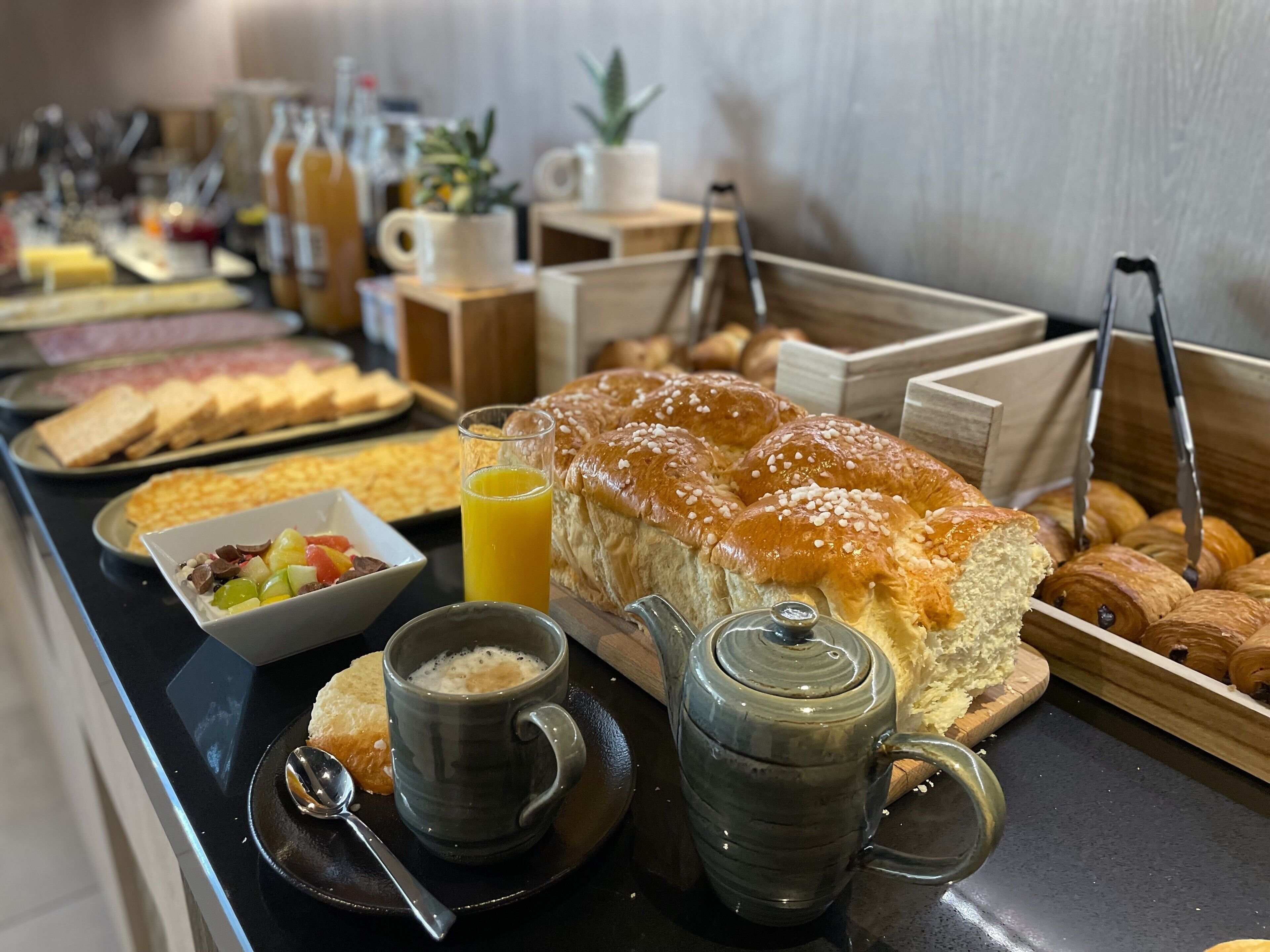 A buffet with various breakfast items including bread, pastries, and a fruit bowl.