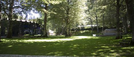 Un parque con un sendero de piedra, bancos y árboles que dan sombra.