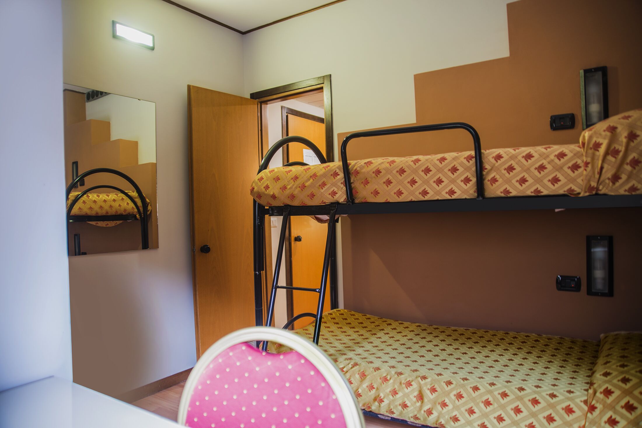 Una camera con un letto a castello, una scala, uno specchio e una porta.