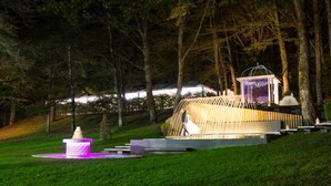 A nighttime outdoor area with a wooden structure, a small platform with a statue, and a fence. - Hotel Giubileo (Pignola)
