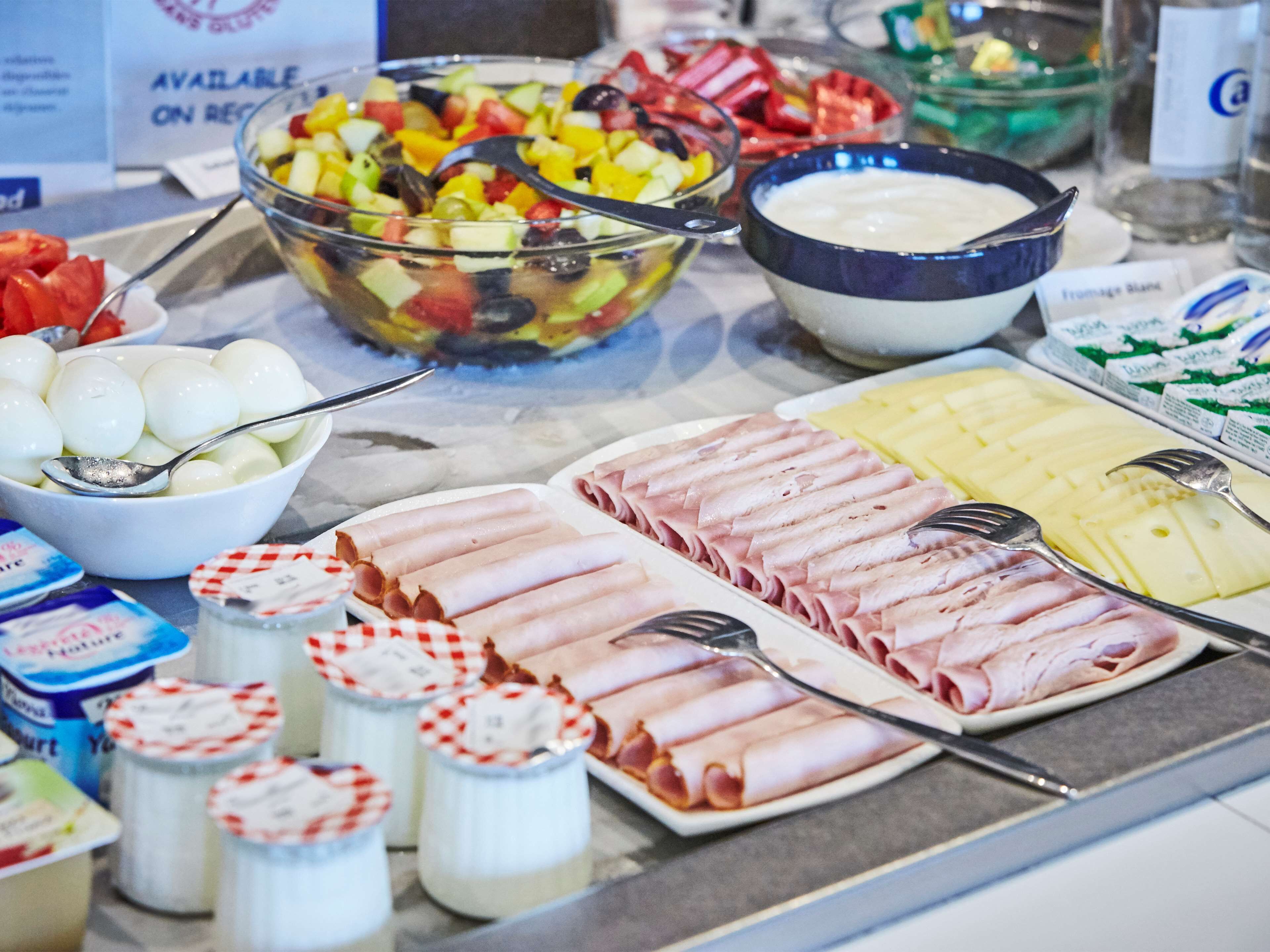 Un bufé con diversas opciones de comida, incluyendo frutas, verduras, carnes y productos lácteos.
