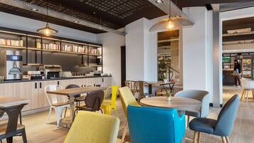 Een modern café met een bar, zitplaatsen en boekenkasten.